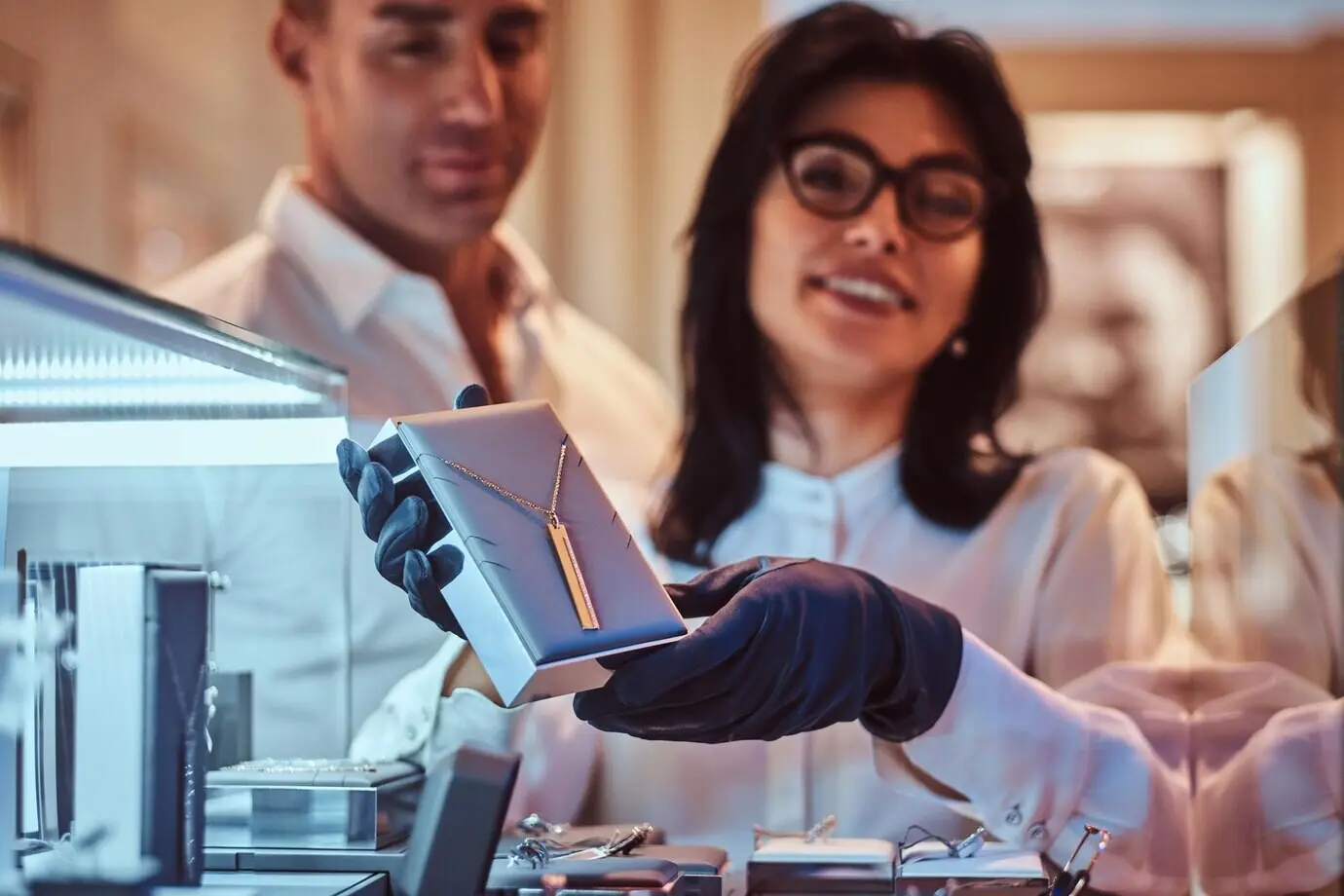 Женщина-консультант показывает эксклюзивное золотое ожерелье в роскошном ювелирном магазине.